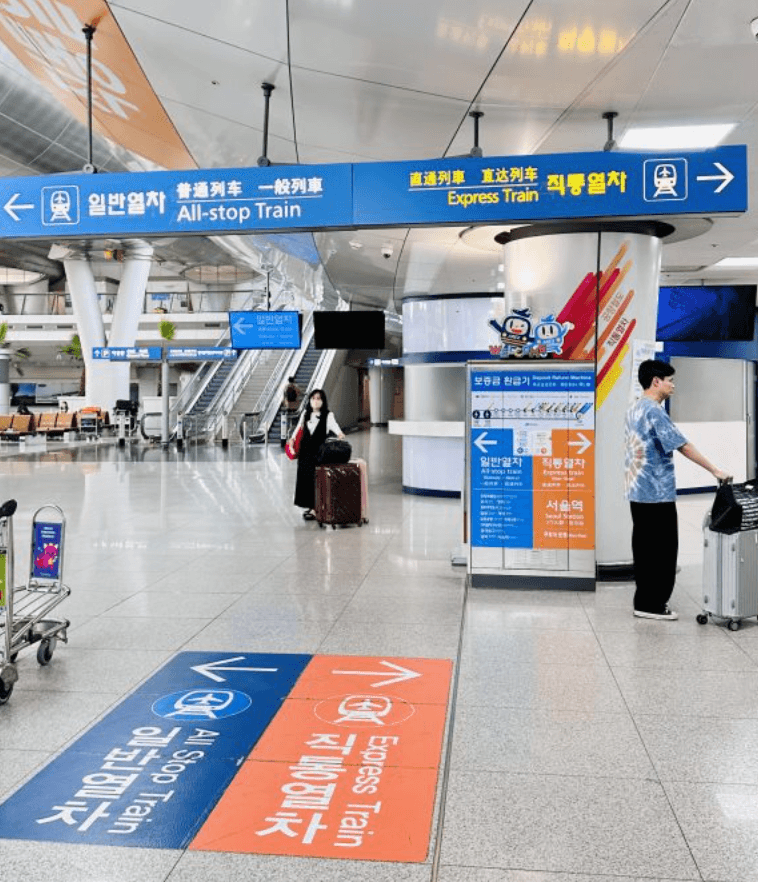 Floor markings at Incheon International Airport pointing left for the All-stop Train and right for the Express Train, with matching overhead signage