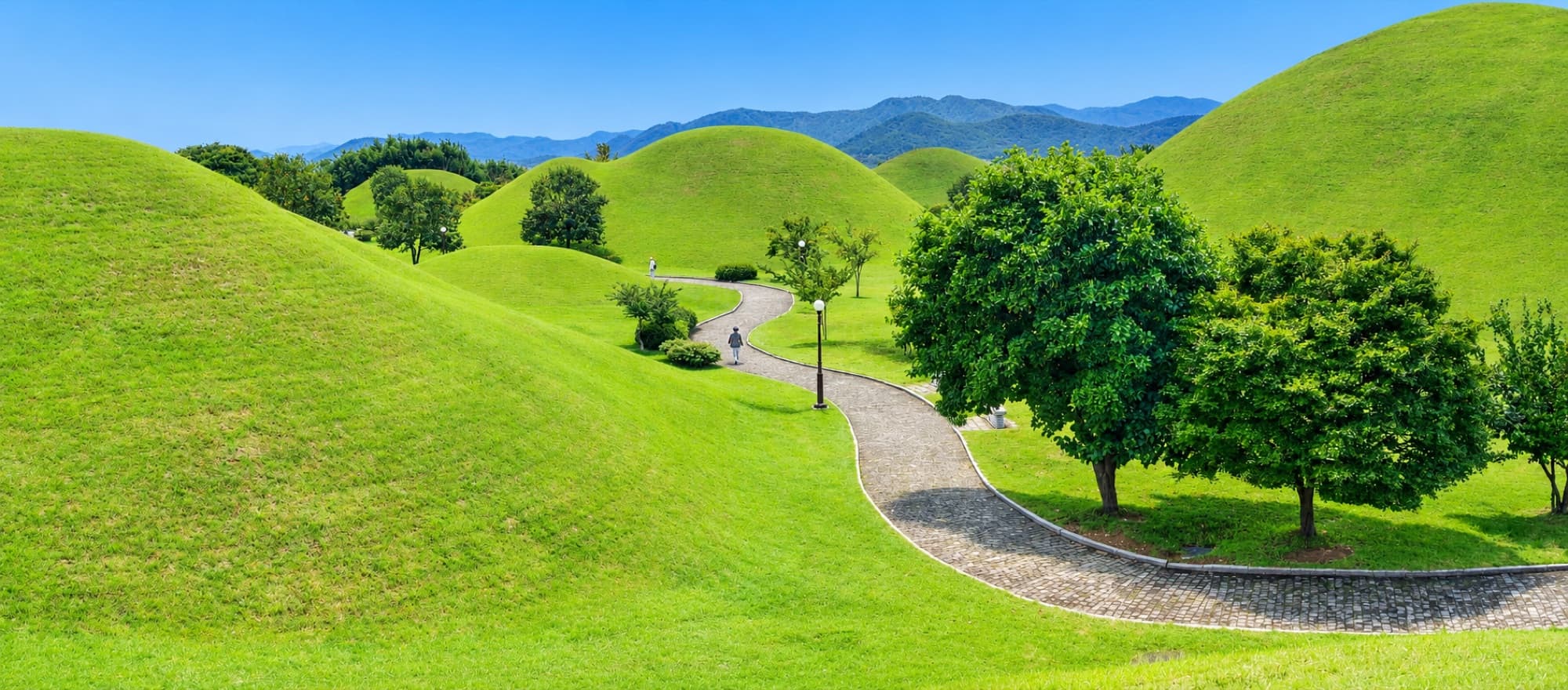 A path winding between the grass-covered royal tomb mounds of Daereungwon, Gyeongju