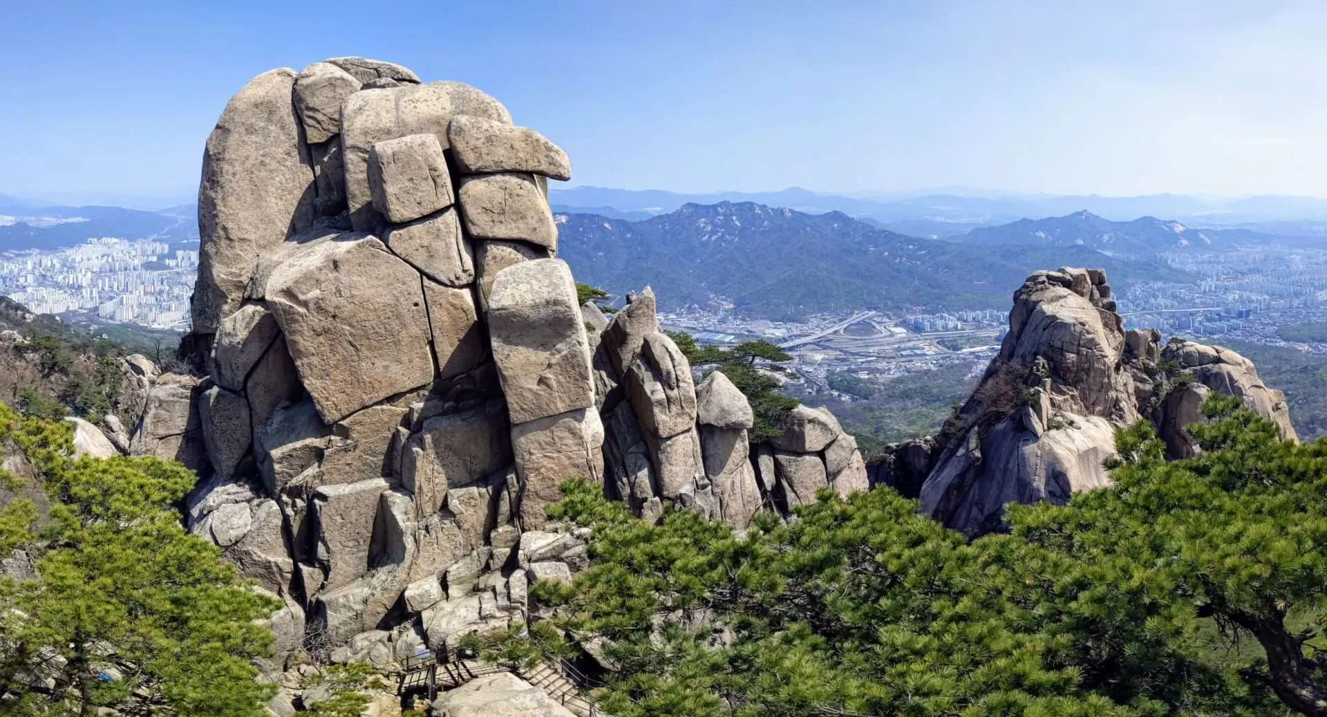 A granite rock formation on a mountain ridge overlooking the Seoul skyline
