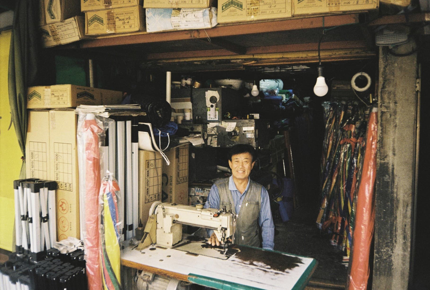 A craftsman at a sewing machine in a small workshop, surrounded by tools and materials