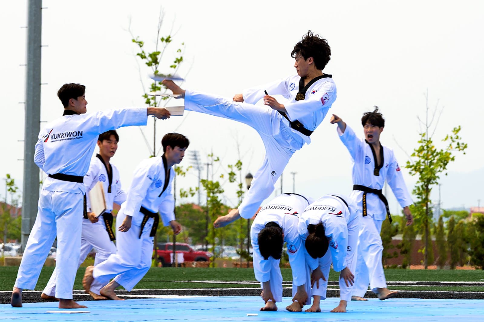 A taekwondo demonstration team performing, one athlete mid-flying kick